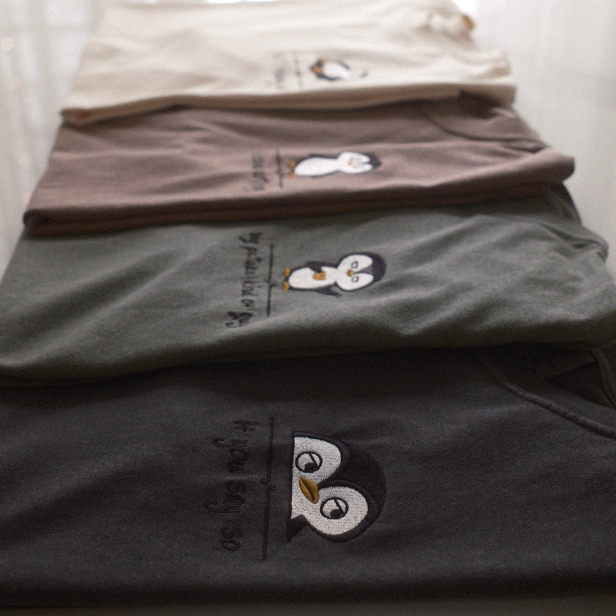 Stack of Desk Face embroidered t-shirts in four colors